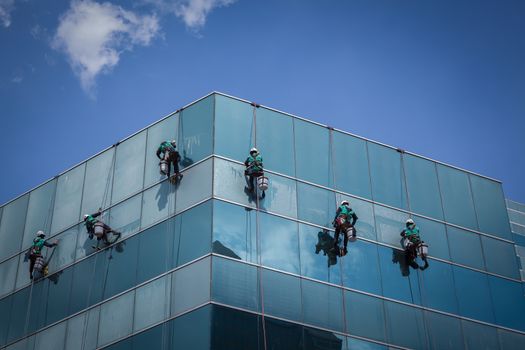 group of workers cleaning windows service on high rise building