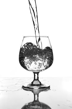 wine glass with water pouring on glass table (gray scale)