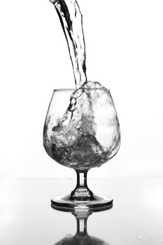 wine glass with water pouring on glass table (gray scale)