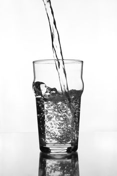 wine glass with water pouring on glass table (gray scale)