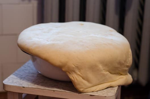 white yeast dough rise through the metal edges of the bowl