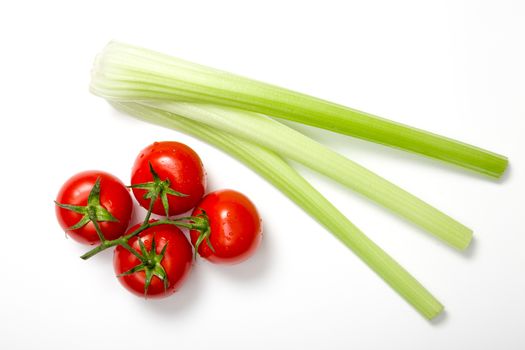 Top view of bunch of fresh tomatoes and celery sticks on white background 