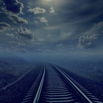 railroad in night to horizon in fog. moonlight in cloudy sky