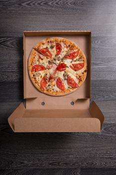 Italian pizza with ham and tomatoes in box, on gray table background 