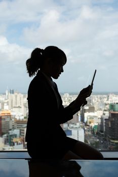 Silhouette of Asian business woman using tablet in a room, concept of technology or communication.