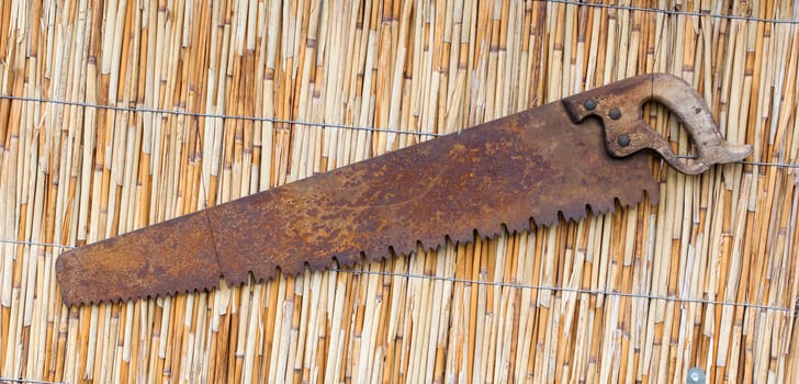 Very old rusted saw with wooden handle