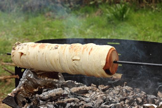 outdoor cooking kurtos kalacs on camp fire, traditional transylvanian cake