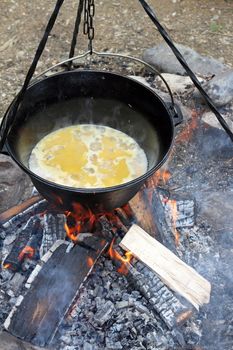 making food on camp fire, cooking in big metal cauldron 