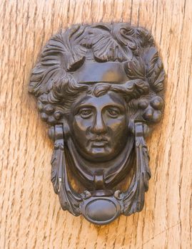 Medieval bronze knocker on the wooden door. Bologna, Italy.