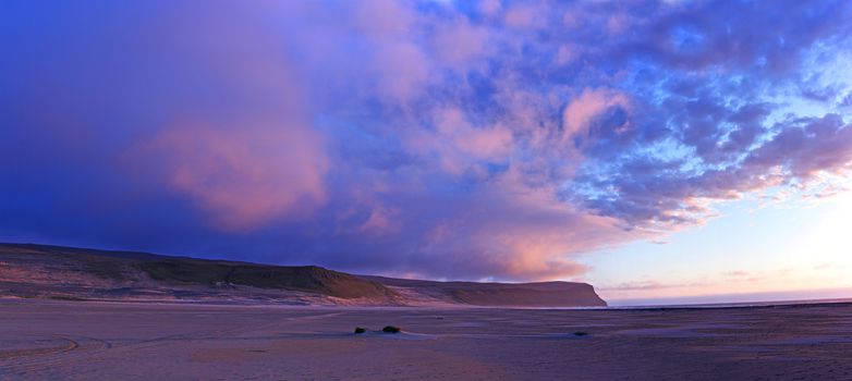 Sunset at the white beach at Iceland ocean coast. Panorama.