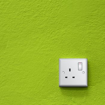 simple white electric great britain socket on green wall