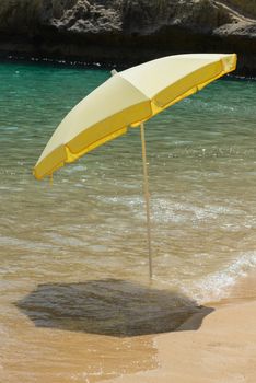 Yellow parasol standing in water on the beach