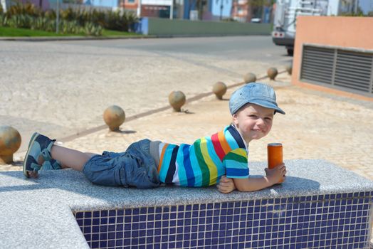 Cute happy little boy lying with drink