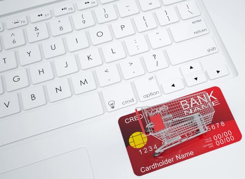 Shopping trolley and credit card on the keyboard. View from above