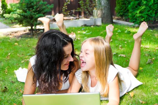 Smiling mother and daughter rest upon herb in summer