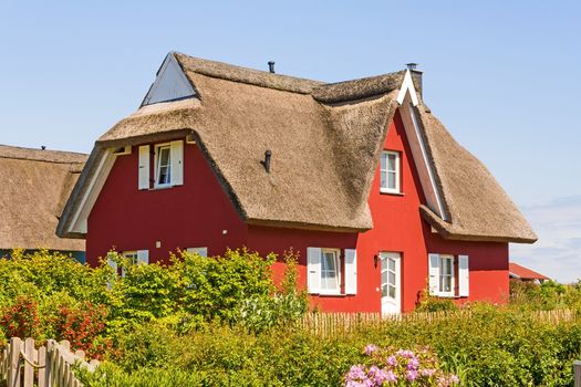 red thatched-roof vacation home with garden