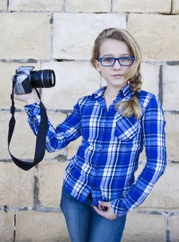Aconfident teenager with glasses holding a SLR camera, taking a selfie