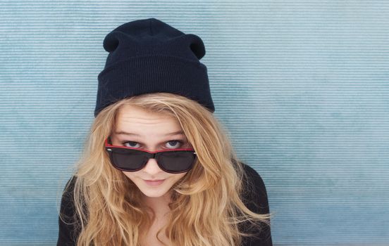 A teenage girl looking up with sunglasses and a beenie