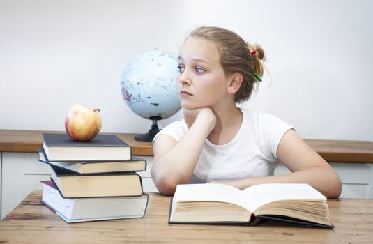 A high school student daydreaming doing her homework