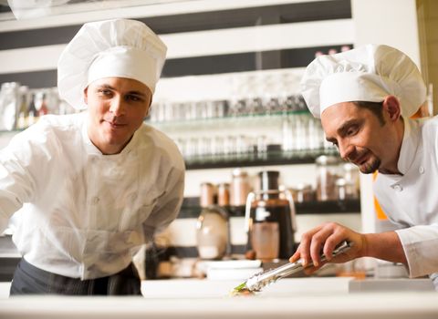 Young chefs preparing delicatessen dishes 