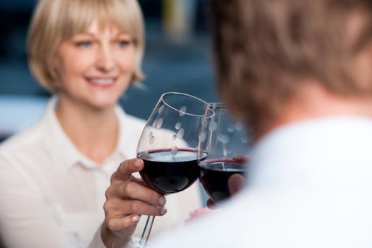 Attractive couple raises a glass of red wine in cafe