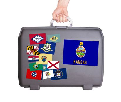 Used plastic suitcase with stains and scratches, stickers of US States, Kansas