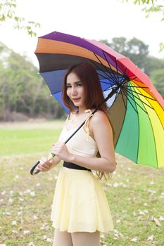 Woman holding multicolored umbrella On the grass in the park.