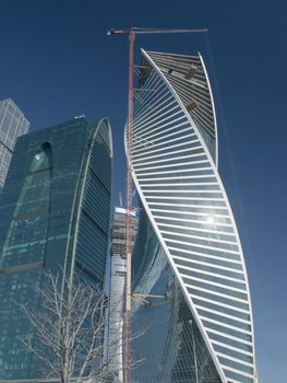 Tower office building under construction with elevating crane