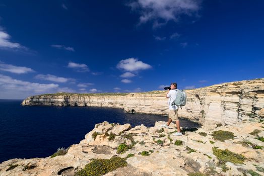 Men taking picture of coast line near Azure Window on Gozo Island, Malta