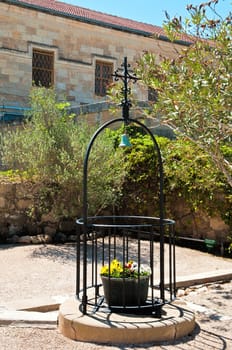 Cross and bell, over basket with fresh flowers fenced with metal rods