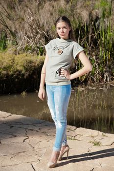 Fashionable girl in blouse and jeans near the backwater with reeds