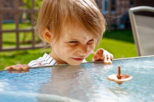 Child unwound spinner on a glass table and waiting when he stops