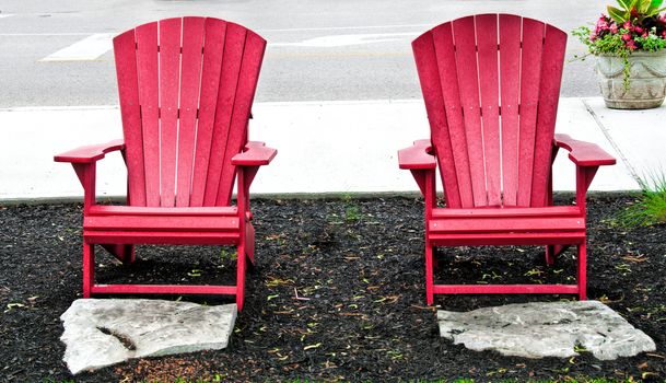 Two red garden chairs and two stone footrests
