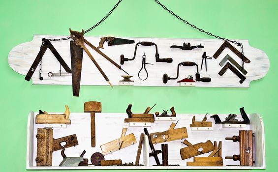 Woodworking tools, retro, two stands of white against the green wall
