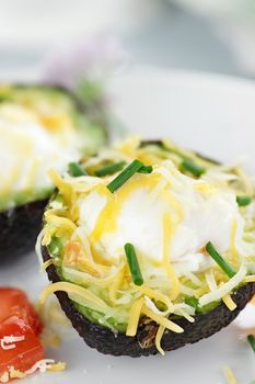 Eggs with cheddar cheese baked in fresh avocados and garnished with chives. Extreme shallow depth of field.