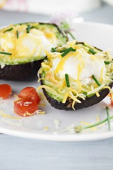 Eggs with cheddar cheese baked in fresh avocados and garnished with chives. Extreme shallow depth of field.