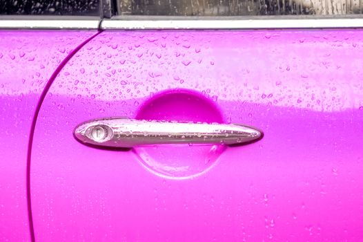 chromed door lever on a pink vehicle panel