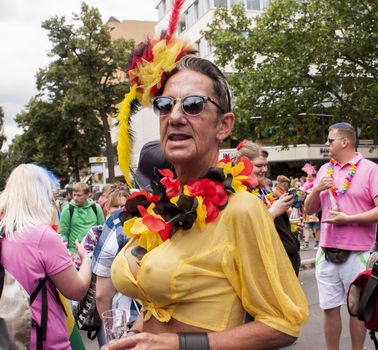 BERLIN, GERMANY - JUNE 21, 2014: Christopher Street Day.Crowd of people Participate in the parade celebrates gays, lesbians, bisexuals and transgenders.Prominent in the image a senior male man with big breasts.