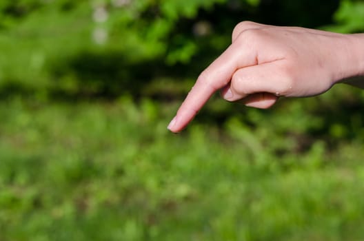 womans hand with water drop on the end of the finger on nature background