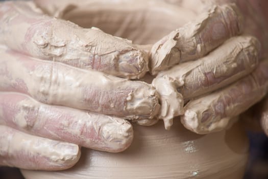 Hands of a potter, creating an earthen jar on the circle