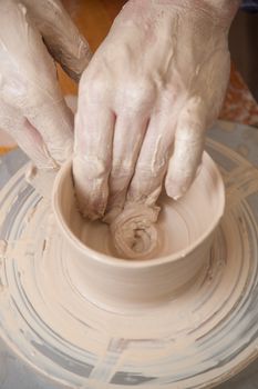 Hands of a potter, creating an earthen jar on the circle