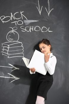 Cute little girl standing by a black school board