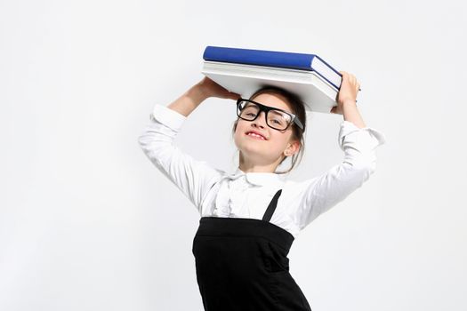 Girl in school uniform on a white background with books on her head