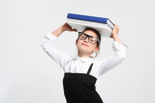 Girl in school uniform on a white background with books on her head