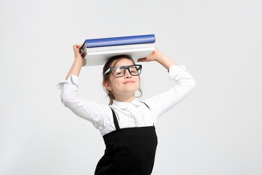 Girl in school uniform on a white background with books on her head