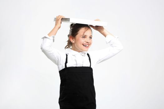 Girl in school uniform on a white background with books on her head