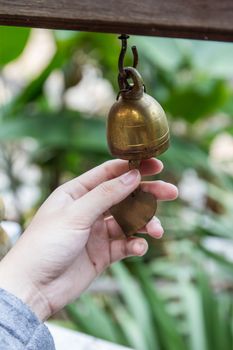 Hand ringing small Thai style bell, typically in temple