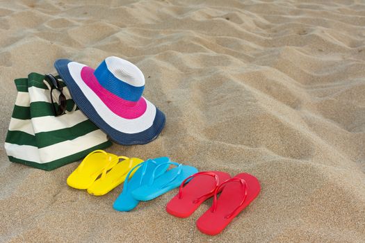 Summer concept of straw hat, bag, sunglasses and flip flops on a tropical beach.