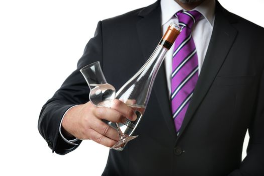 Business man in dark suite with a grappa glas and a bottle with alcohol