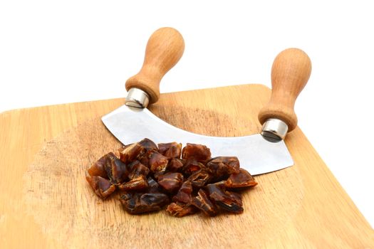 Chopped dates with a rocking knife on a wooden chopping board